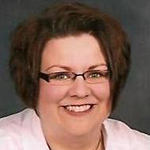 Portrait of woman with short dark hair wearing glasses ans a white shirt.
