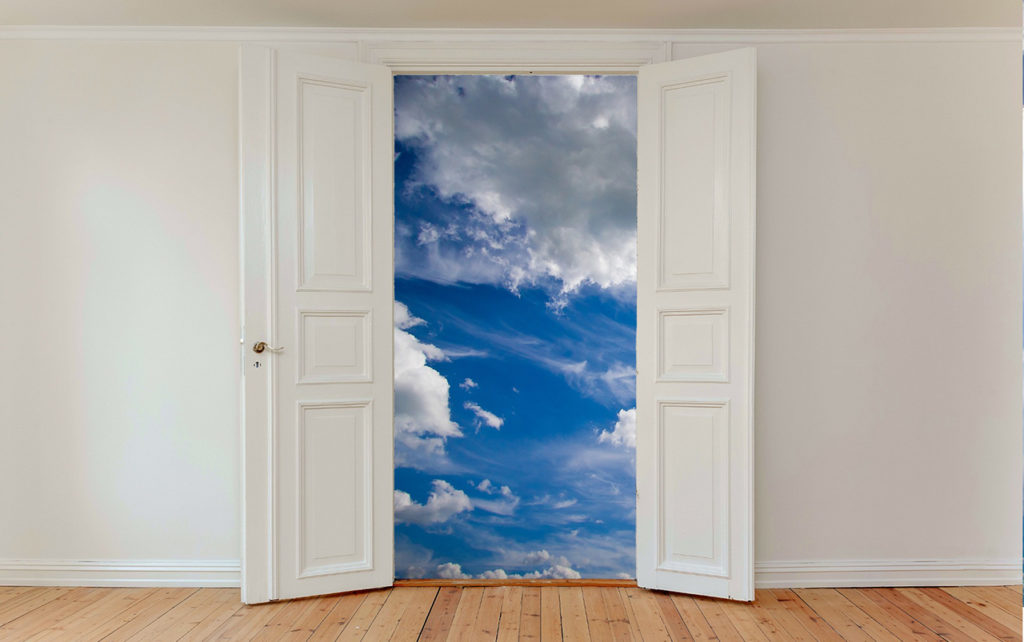 French style doors open with blue sky and clouds on the other side.