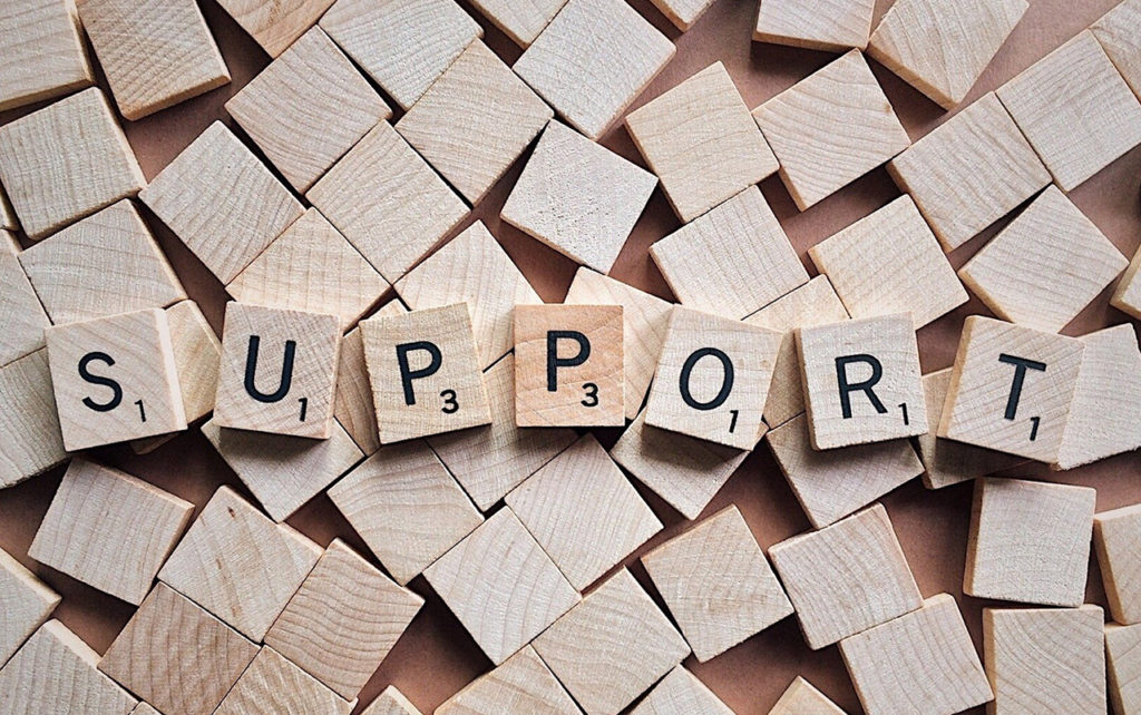 Scrabble tiles covering a table. The word "support" is spelled out with some of the tiles.