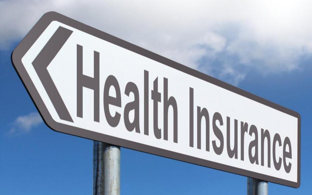 Road sign pointing to the left with the words Health Insurance on it.