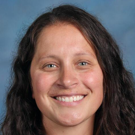Professional headshot of a smiling female with a brown long hair against a blue background.