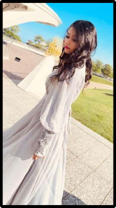 Amber, a 2024 graduate, is wearing a long dress standing on a brick sidewalk for her Senior photo